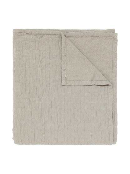 A folded light beige textured muslin blanket 