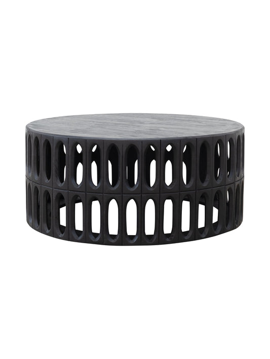A round, drum-shaped coffee table made of solid hand-carved mango wood with a geometric pattern of holes and supports, without any visible legs.